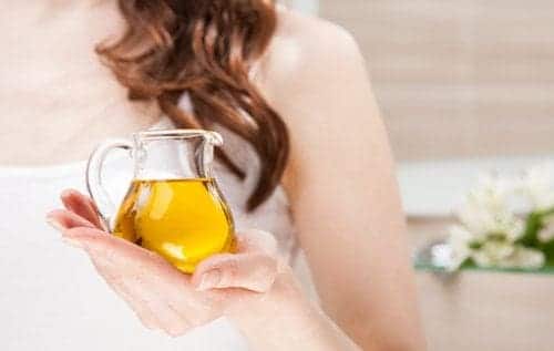 كيفية التقليل من تجاعيد الوجة طبيعيا 3 سيدة تحمل إبريق زيت زيتون: التقليل من ظهور التجاعيد
